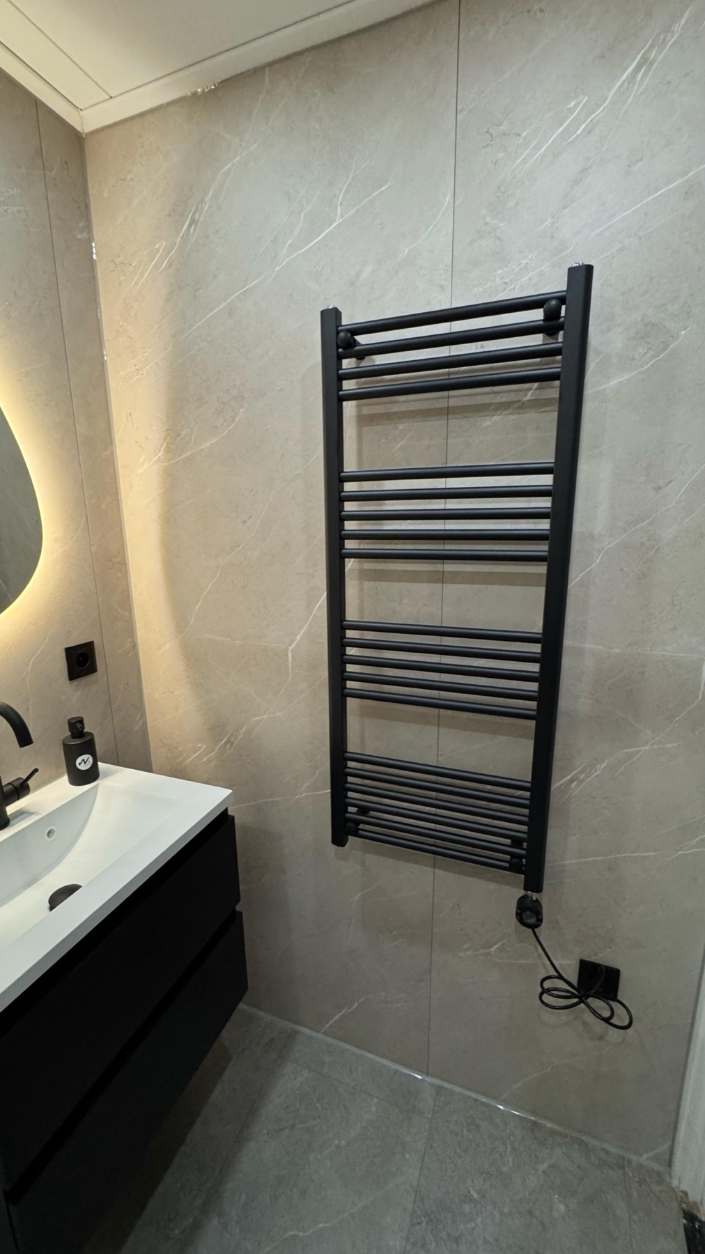 Zwarte radiator tegen marmerlook wand