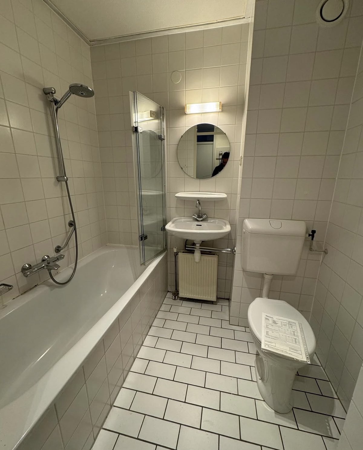 Badkamer voor renovatie met witte tegels en ligbad