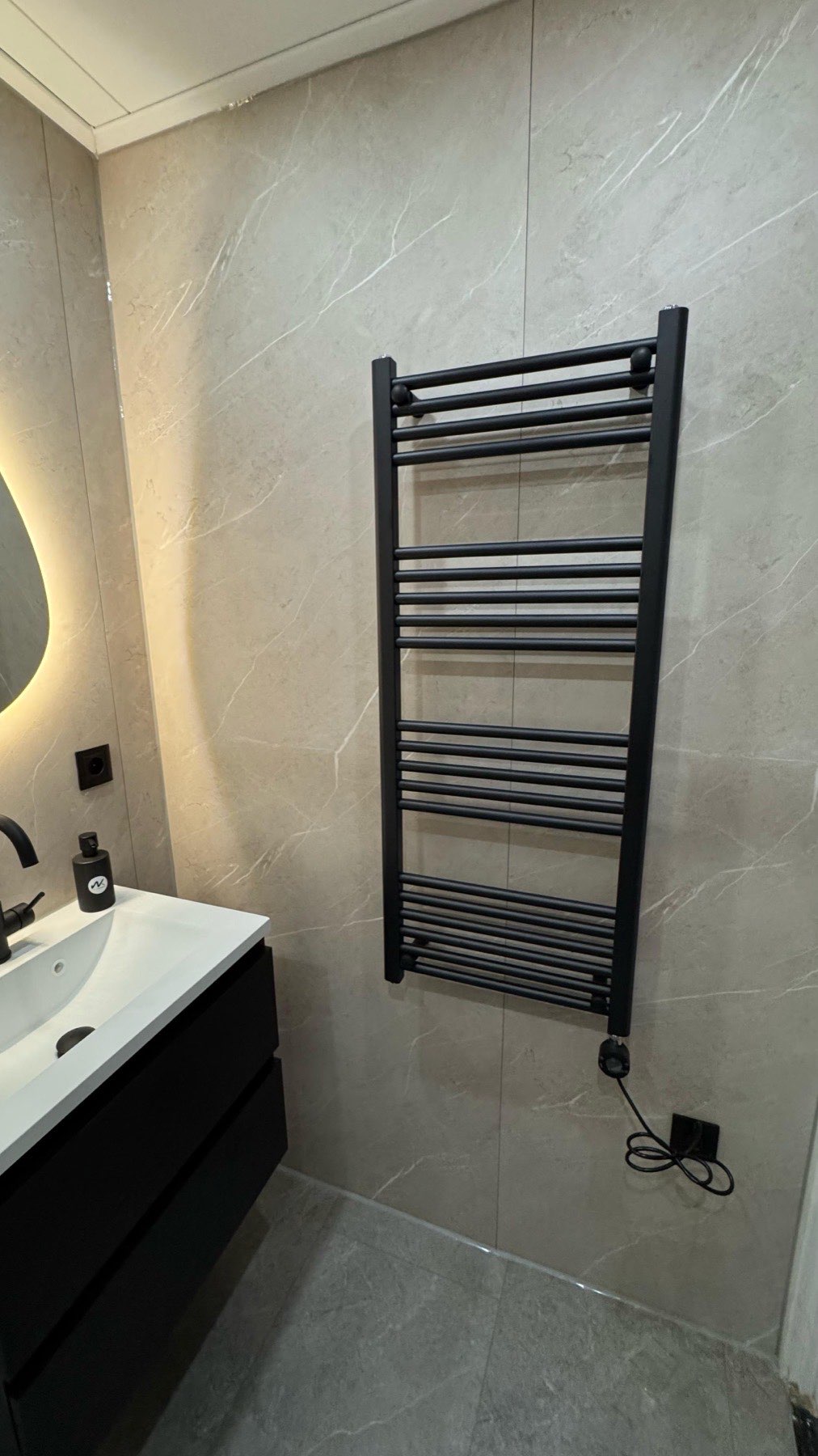 Zwarte radiator tegen marmerlook wand