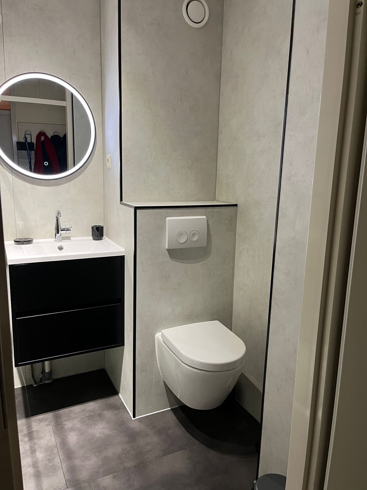 Toiletruimte met lichte wandpanelen en zwart wastafelmeubel